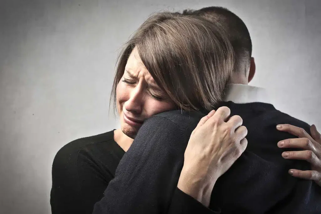 woman grieving hugging man